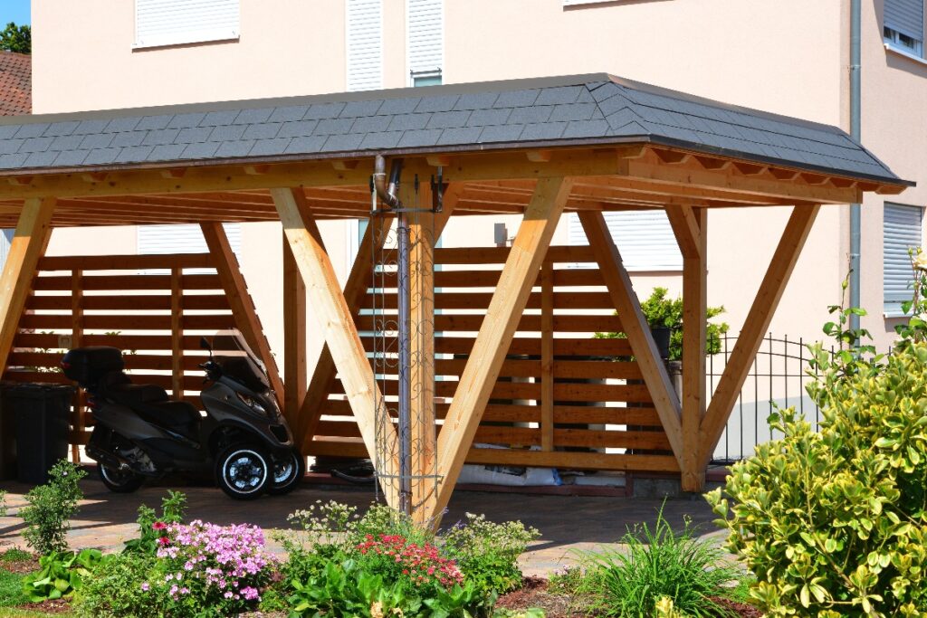 Neuer Carport aus lasiertem Holz mit Kupfer-Dachrinne und Regenfallrohr und automatisches Metall-Einfahrtstor, alpine Architektur